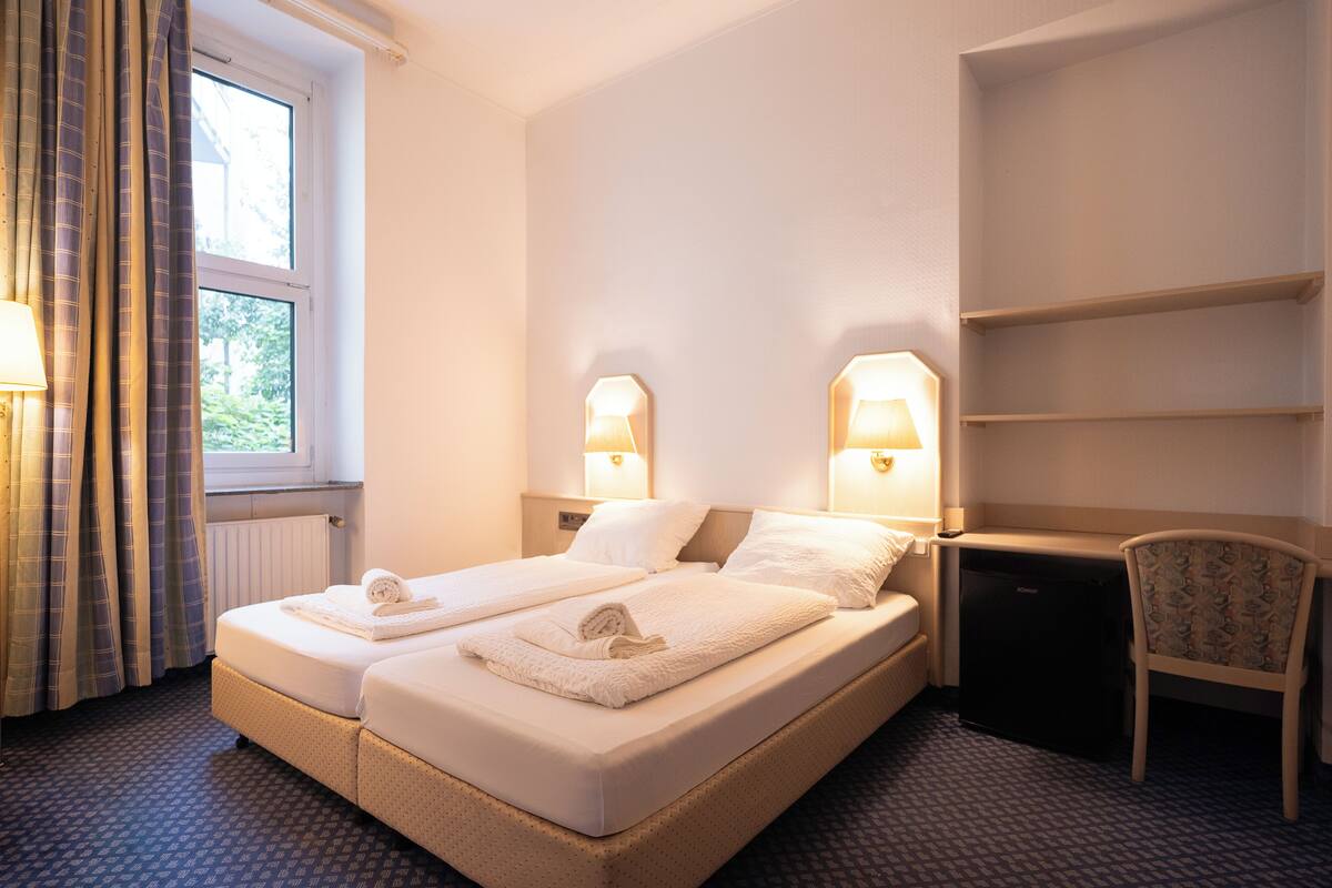 Una habitación de hotel con dos camas, una silla y un escritorio pequeño.