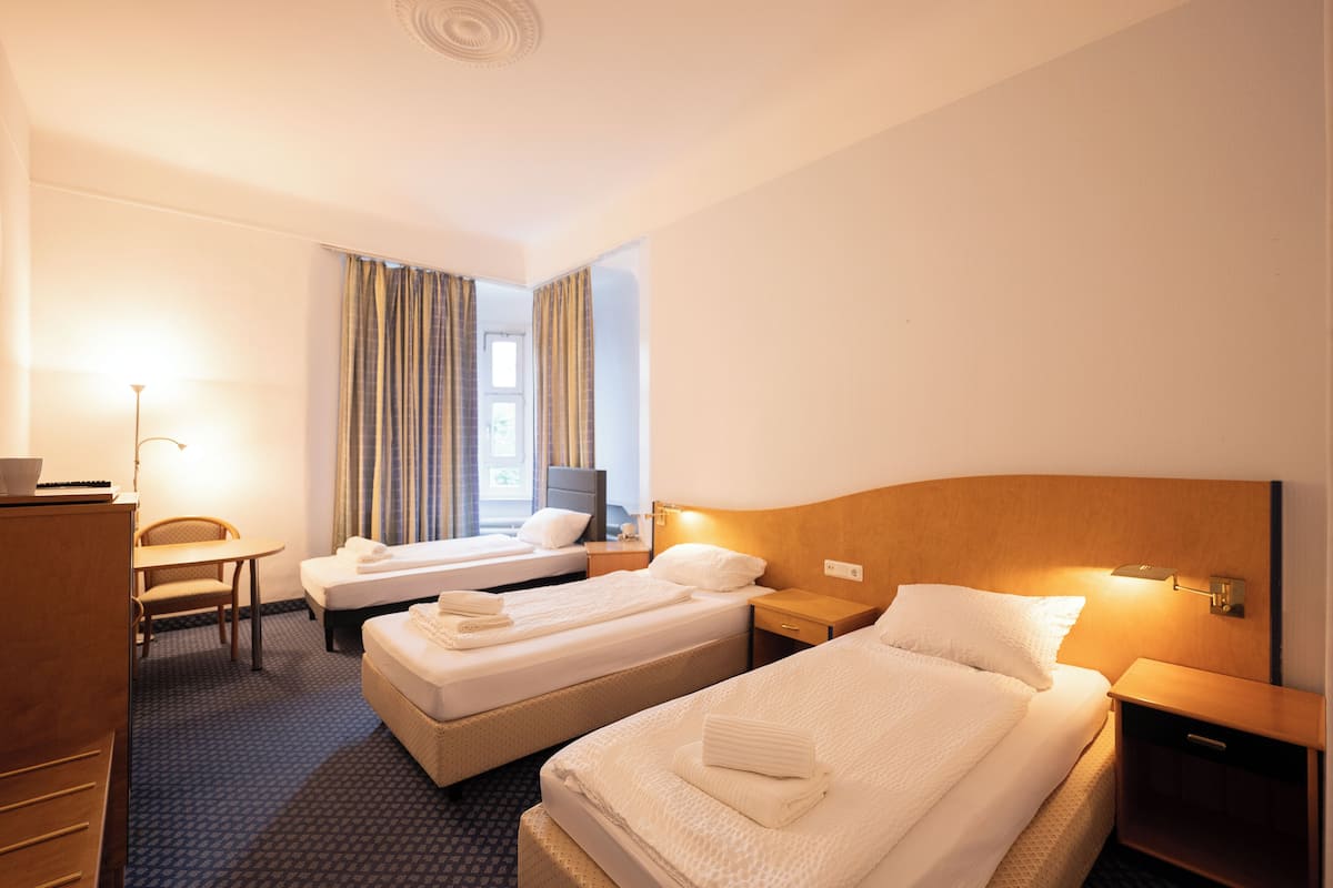 Habitación de hotel con dos camas, un escritorio, una silla y un televisor.