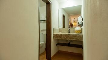 A bathroom with a toilet, sink, mirror, and towel rack.