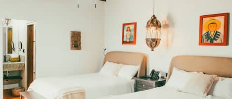 A bedroom with two beds, a bench, a ceiling fan, and a nightstand with a phone.