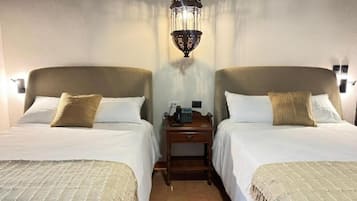 A hotel room with two beds, a nightstand, a lamp, and a telephone.