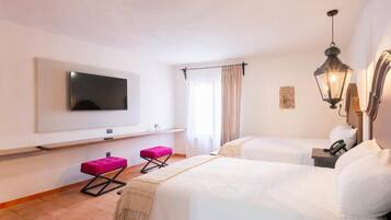 A hotel room with two beds, a TV, a small table, a bench, and a hanging light fixture.