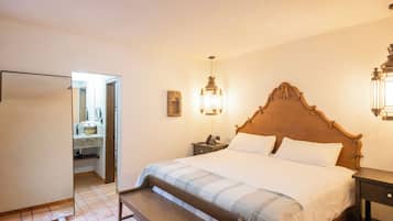 A bedroom with a wooden bed, bedside lamps, a nightstand, and a mirror.