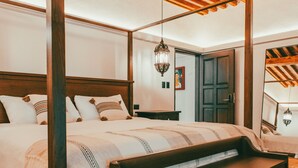 Una cama con dosel de madera y un ventilador de techo, un banco y piso de baldosas.