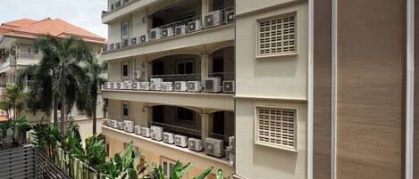 A multi-story hotel with balconies, air conditioning units, and lush greenery.