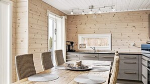 A wooden interior with a dining table, chairs, a kitchen area, and a window. - 4 Star Holiday Home in Fall (Søndre Land)