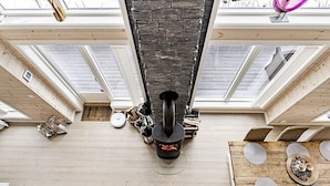 A high-ceilinged room with a stone fireplace, skylights, and a dining area with a wooden table and chairs. - 4 Star Holiday Home in Fall (Søndre Land)