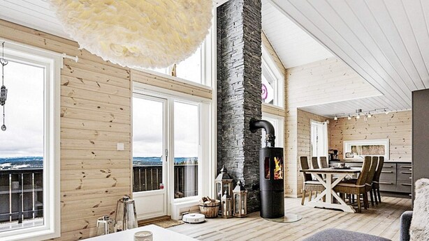 A spacious living area with a high ceiling, wooden walls, a stone fireplace, and a balcony with a view. - 4 Star Holiday Home in Fall (Søndre Land)