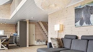 A modern interior with a grey sofa, a white coffee table, and a wooden staircase. - 4 Star Holiday Home in Fall (Søndre Land)