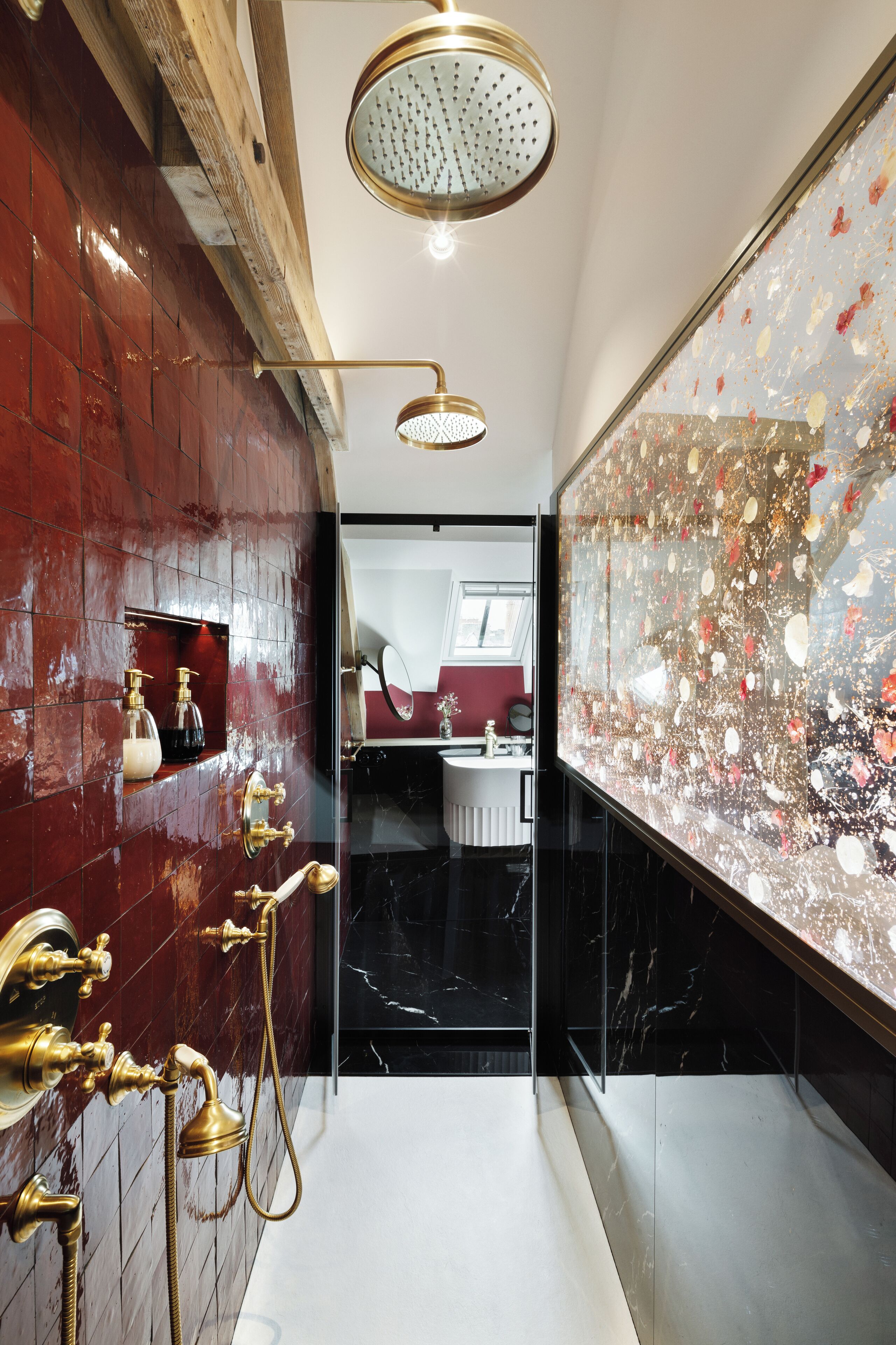 Un baño moderno con ducha, tocador con espejo y pared de azulejos rojos.