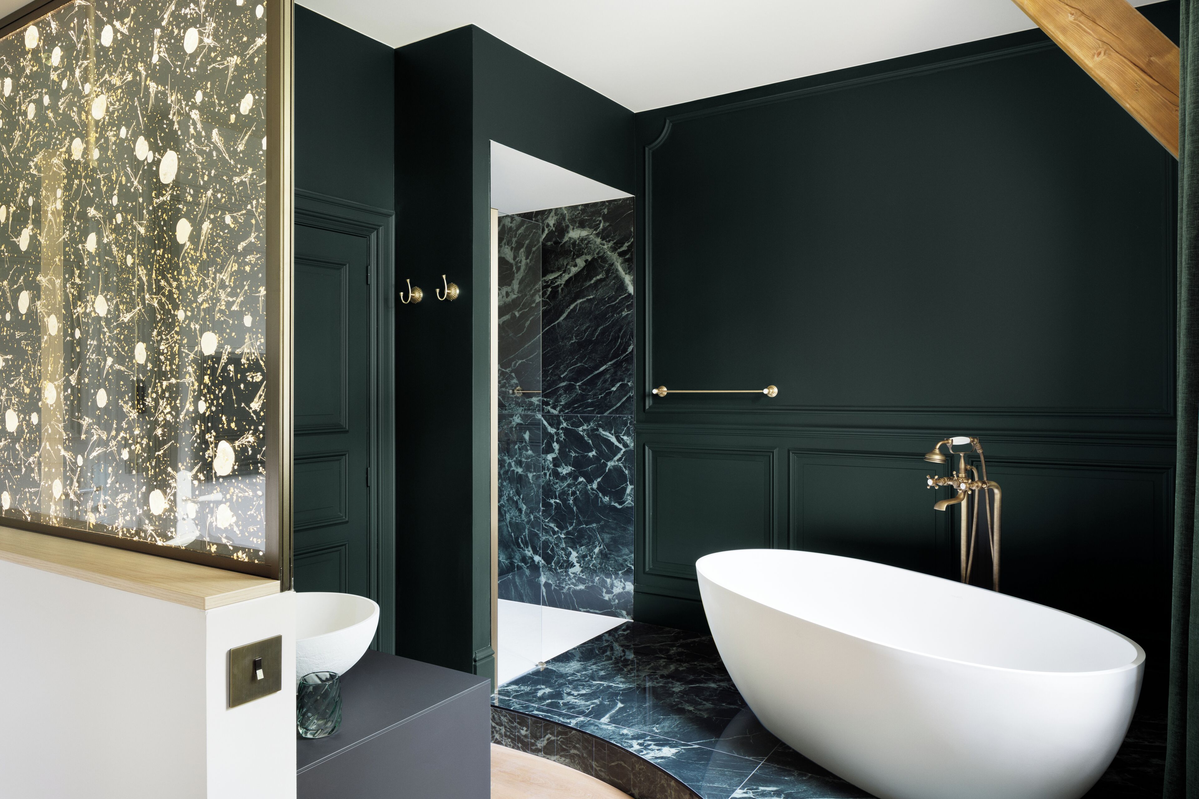 A modern bathroom with a freestanding bathtub, dark walls, and marble flooring.