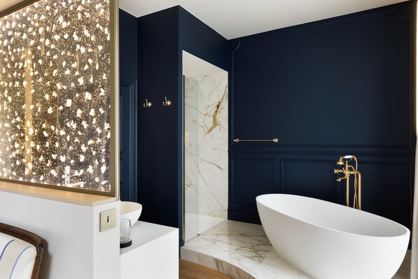 A modern bathroom with a freestanding bathtub, marble walls, and a glass shower enclosure. - Clos du Cèdre (Dinan)