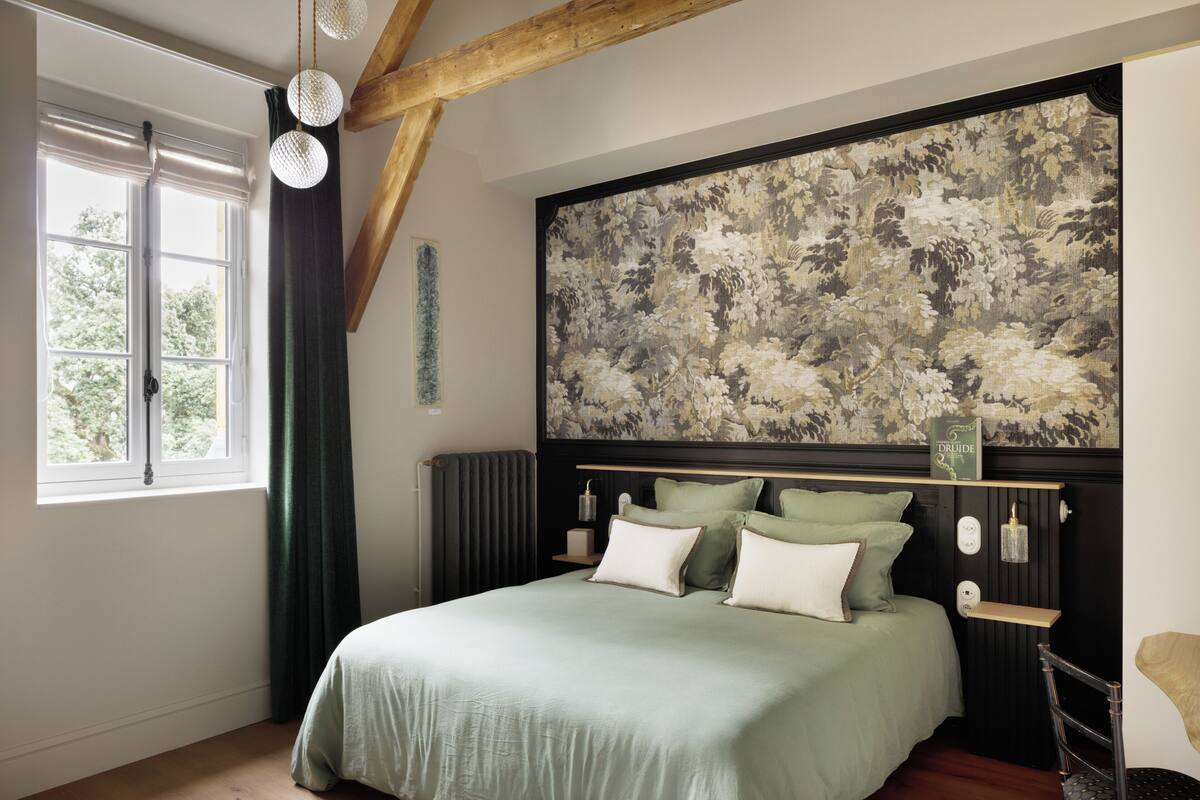 Quarto com cama grande, janela com cortinas, radiador e uma obra de arte na parede.