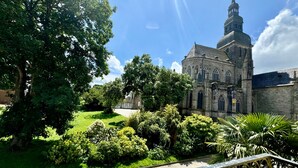 A historic church with a prominent dome and spire, surrounded by lush greenery and a paved pathway. - Clos du Cèdre (Dinan)