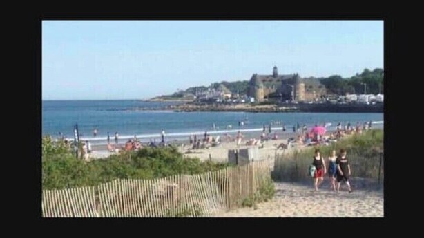 A beach with people walking, a wooden fence, and a building in the background. - TreeFort, ZipLine, Kayaks, Beach6min drive, Vaulted Ceilings, ScreenPorch & Deck (Narragansett)