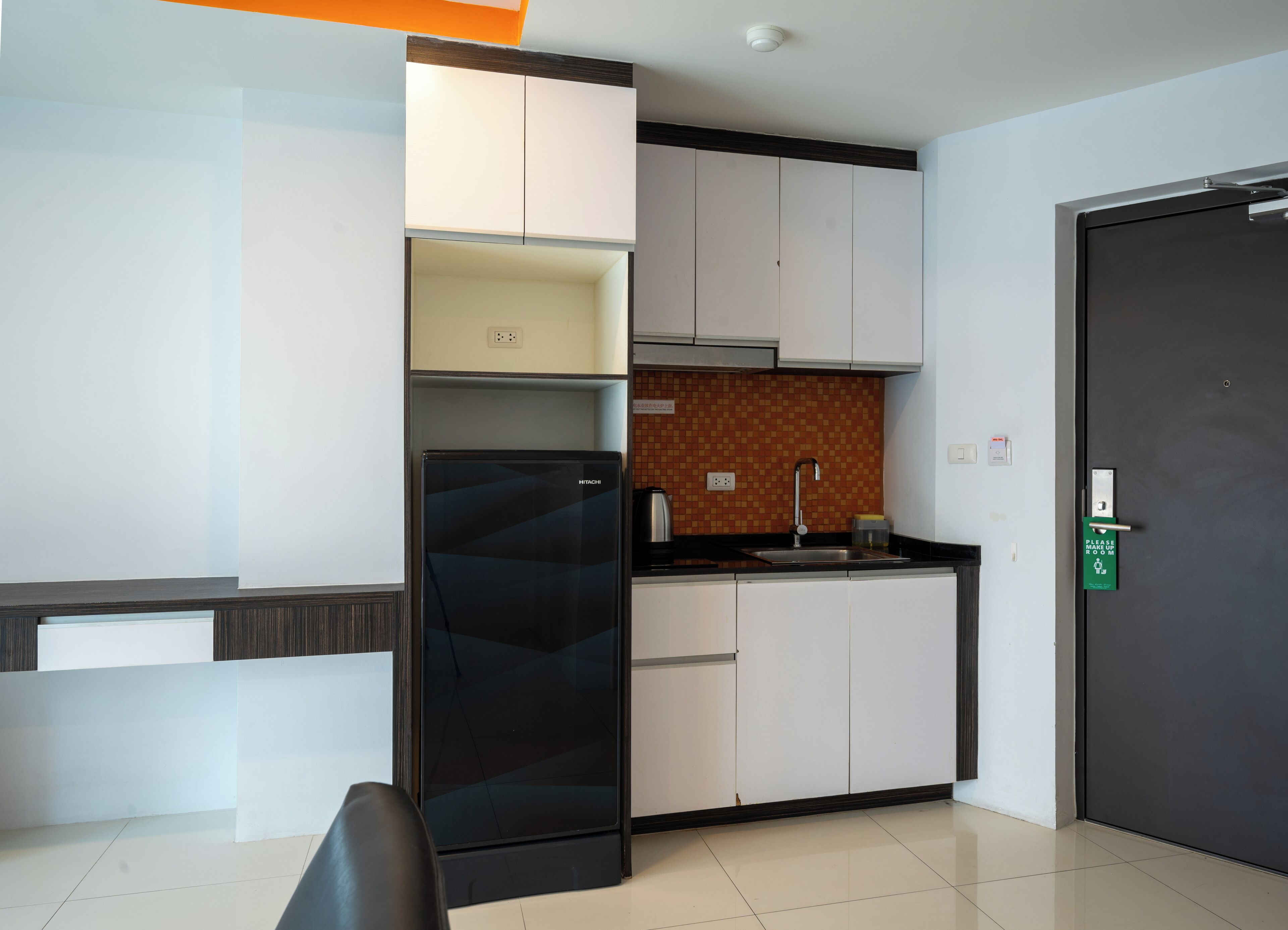 Een moderne keuken met een zwarte koelkast, witte kasten en een betegelde spatwand.