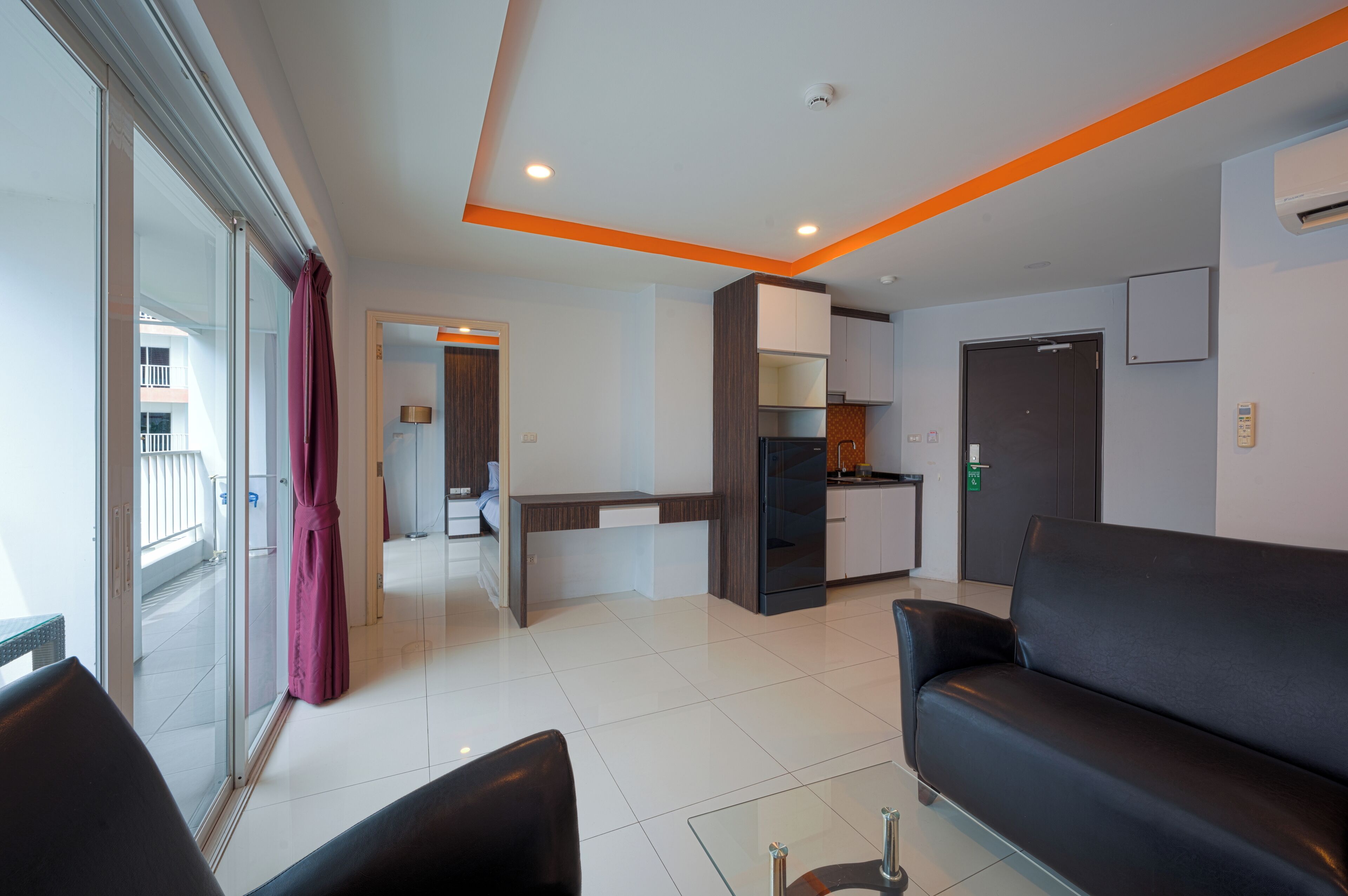A modern living area with a sofa, a dining table, and a kitchen in the background.