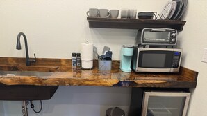 A kitchen with a wooden countertop, a sink, a coffee maker, a microwave, and a trash can. - Cozy Cabin with Stunning Views (Seward)