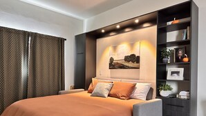 Een moderne slaapkamer met een groot bed, een inbouwboekenplank en een kunstwerk aan de muur.