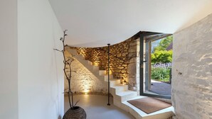 A modern interior with a stone wall staircase, a woven basket, and a view of a garden.
