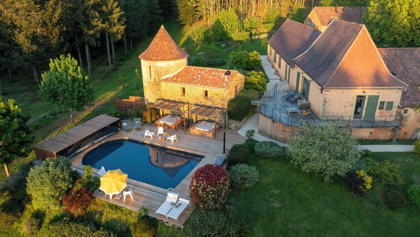 A large house with a swimming pool, outdoor seating, and a garden.