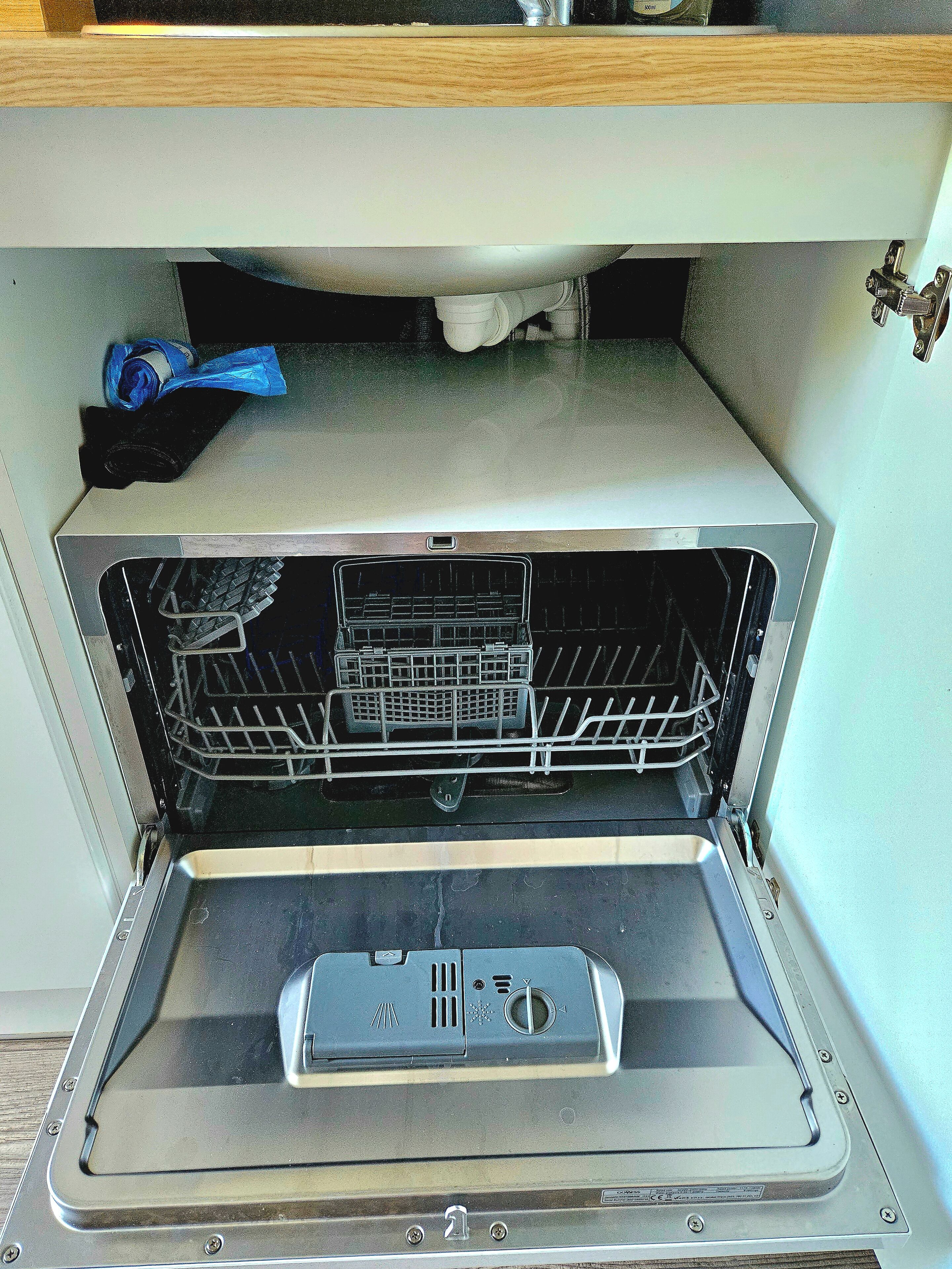 An open dishwasher with a control panel and a rack inside.
