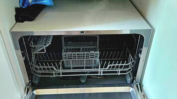 An open dishwasher with a control panel and a rack inside.