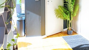 A modern hallway with a wooden floor, a white door, and a potted plant. - Cofy Rentals Tallinn (Tallinn)