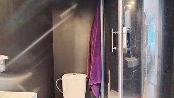 A compact bathroom with a toilet, a shower enclosure, and a sink.