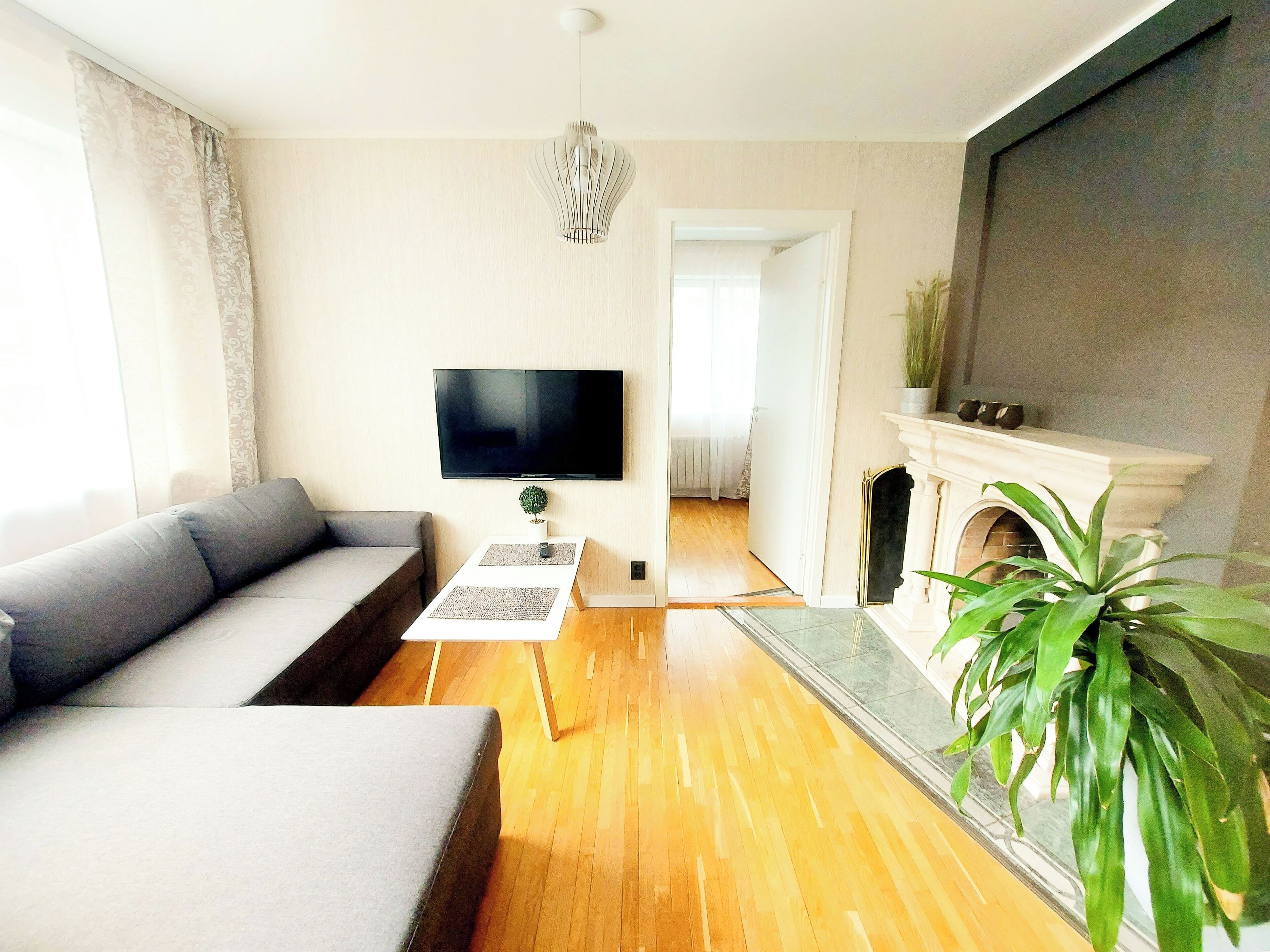 Una sala de estar con un sofá gris, un televisor de pantalla plana, una mesa de centro y una chimenea.