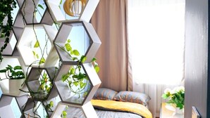 A modern bedroom with a geometric shelving unit, a bed with patterned bedding, and a window with curtains. - Cofy Rentals Tallinn (Tallinn)