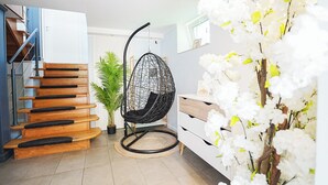 A modern interior with a wooden staircase, a hanging chair, a potted plant, and a white dresser. - Cofy Rentals Tallinn (Tallinn)