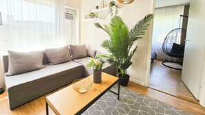 A modern living room with a grey sofa, a wooden coffee table, and a hanging chair. - Cofy Rentals Tallinn (Tallinn)
