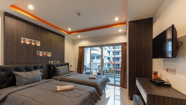 Een moderne hotelkamer met twee bedden, een bureau met een flatscreen televisie en een balkon met uitzicht over de stad.
