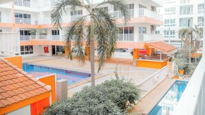 Een meerhoog hotel met een centraal gelegen zwembad, balkons en palmbomen.