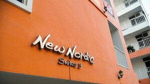 Een hotelschilt met de naam 'New Nordic Suites 3' op een oranje gevel.