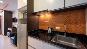 Een moderne keuken met een ingebouwde magnetron, een RVS-spoelbak en een betegelde spatwand.