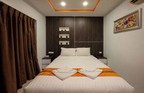 Ein Hotelzimmer mit einem großen Bett, braunen Vorhängen, einem Nachttisch, einer Wandablage und einem Gemälde.