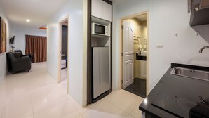 A compact kitchen with a refrigerator, microwave, and sink. There is a dining area with a chair and a table.