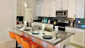 A modern kitchen with white cabinets, a central island with seating, and stainless steel appliances.