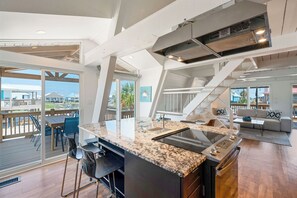 Experience the open-plan living space with a modern kitchen, stove, and sliding glass door leading to a balcony with outdoor seating.