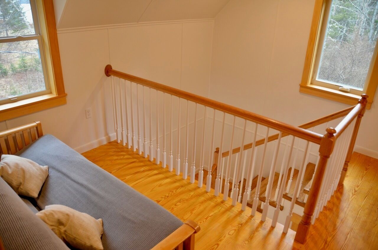 Une pièce avec un escalier en bois, un canapé et une fenêtre.