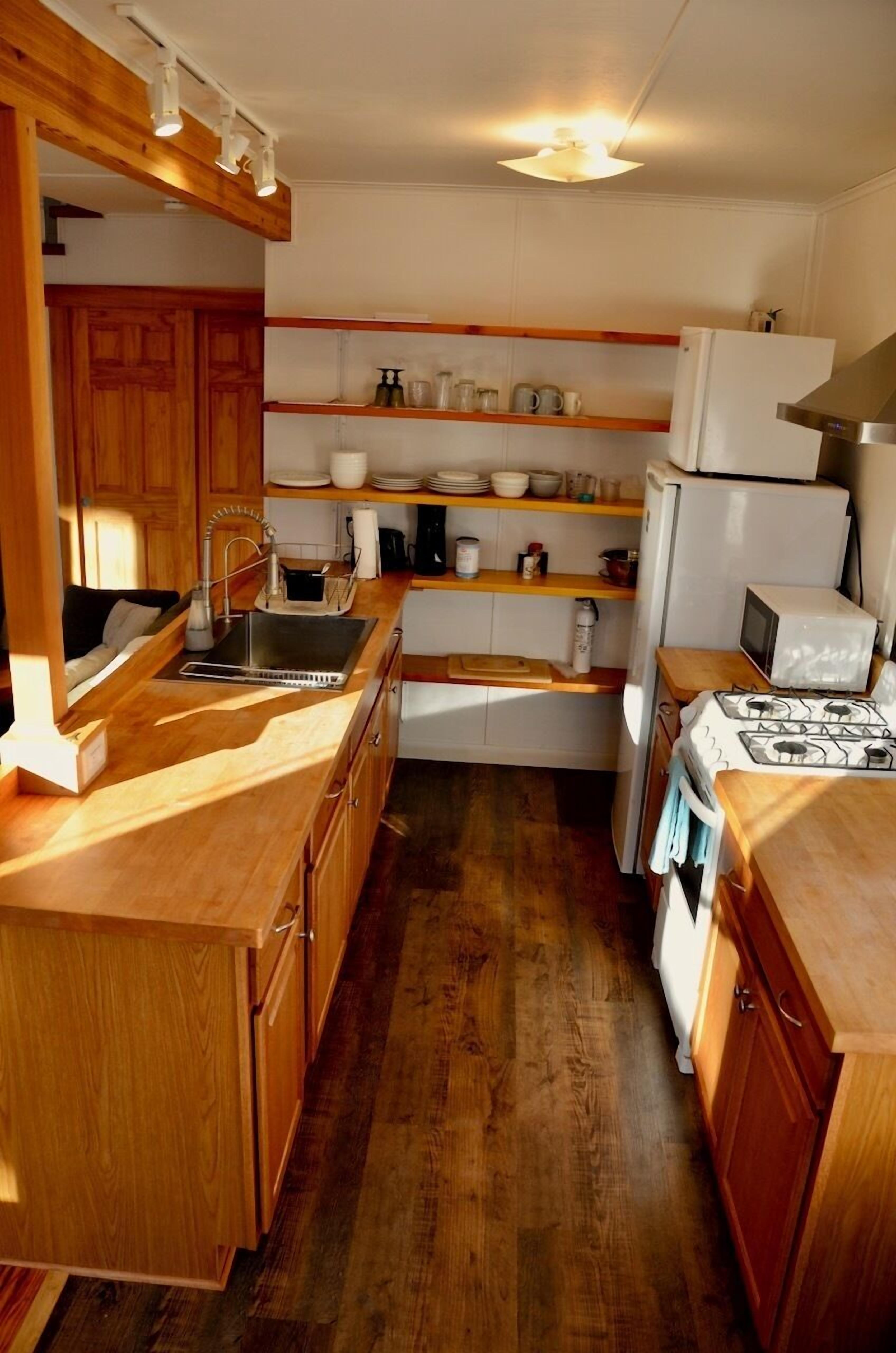 A compact kitchen with wooden cabinets, a sink, a stove, and a refrigerator.