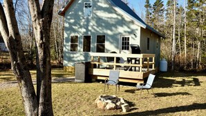 A wooden cabin with a porch, a fire pit, and a view of the surrounding forest. - Peaceful private location, cottage @Acadia NP, Lighthouse, Beaches, Seafood🦞 (Bass Harbor)