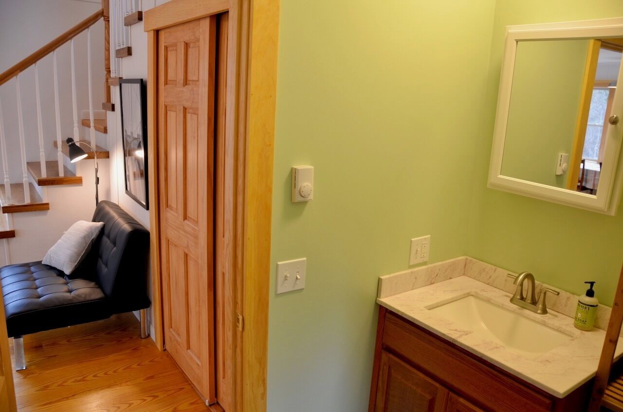A bathroom with a sink, mirror, and wooden door.