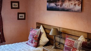 A bedroom with two beds, a nightstand, a lamp, a painting of a mountain landscape, and two framed pictures on the wall. - LUPULUS" apartment.  Ideal for a family holiday (Bilwisheim)