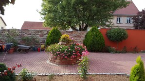 A garden with a brick planter, potted plants, and a wheelbarrow. - LUPULUS" apartment.  Ideal for a family holiday (Bilwisheim)