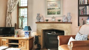 A cozy living room with a fireplace, a television, and a bookshelf. - 2 bedroom accommodation in Crewkerne (Crewkerne)