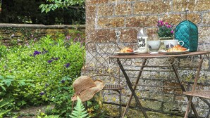 A rustic outdoor setting with a metal table and chairs, a wicker hat, and a bottle of Holy Cow organic whole milk. - 2 bedroom accommodation in Crewkerne (Crewkerne)