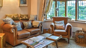 A cozy living room with a leather sofa, armchair, and coffee table. There are books and a basket on the table. - 2 bedroom accommodation in Crewkerne (Crewkerne)